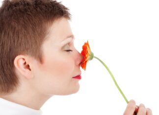 Frau mit kurzen Haaren riecht an Blume