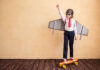 Kind als Flugzeug verkleidet auf Skatebord