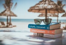 Sonnenbrille auf Bücherstapel am Strand