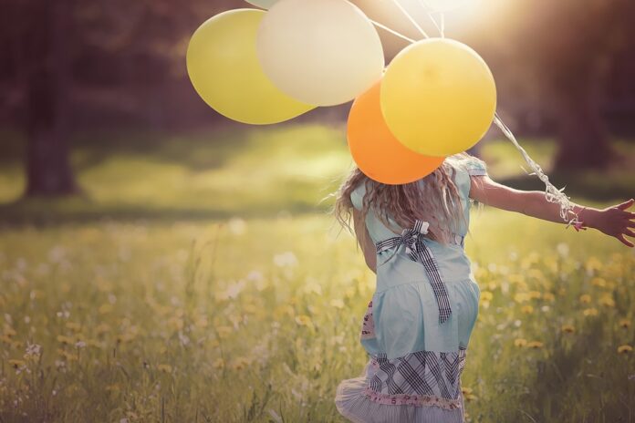 Kind läuft mit Luftballons
