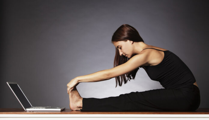 Frau macht Yoga vor dem Laptop