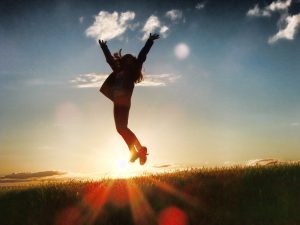 Frau springt vor Sonnenuntergang motiviert in die Luft