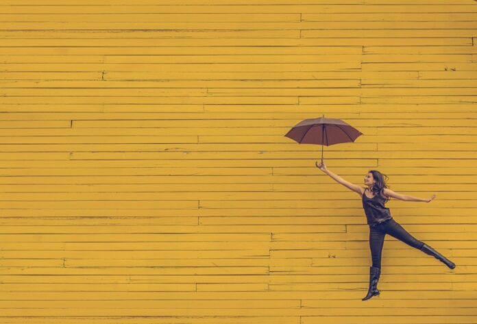 Frau springt hoch mit Regenschirm