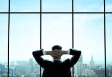 Mann sitzt in riesigen Büro und blickt auf die Skyline von New York