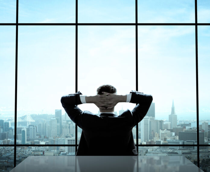 Mann sitzt in riesigen Büro und blickt auf die Skyline von New York