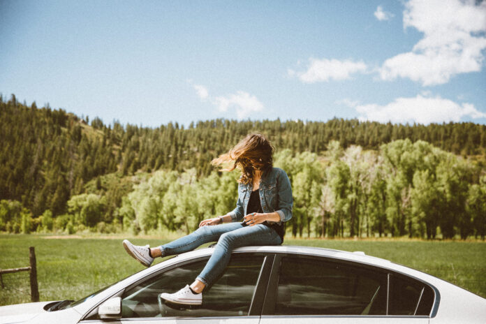 junge Frau sitzt auf einem Auto