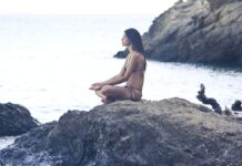 Frau meditiert auf einem Felsen