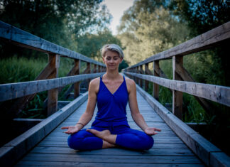 schöne Frau bei Yoga auf Holzbrücke