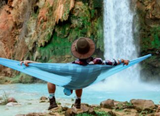 Mann liegt völlig entspannt in einer Hängematte vor einem Wasserfall