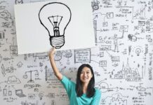 Frau zeichnet eine Glühbirne auf ein Vision Board