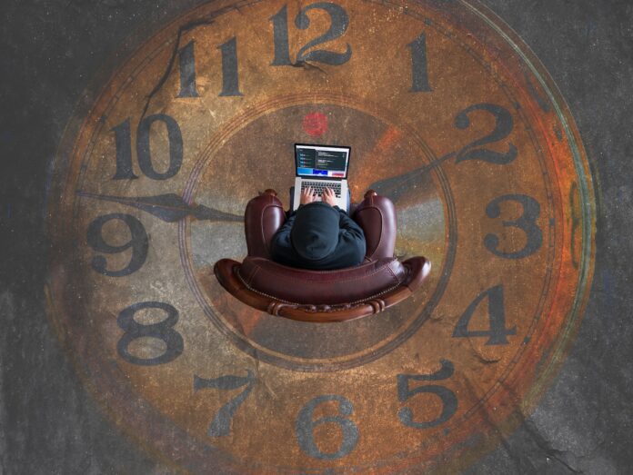 Mann sitzt innerhalb einer Uhr und kontrolliert die Zeit