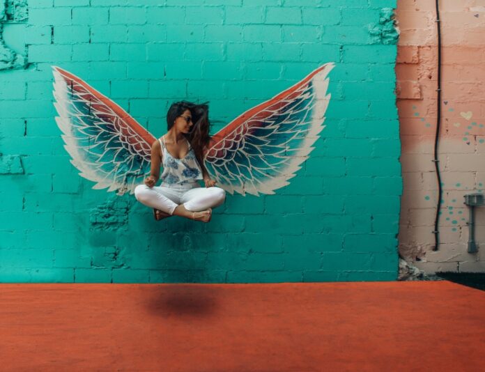 Frau springt in die Luft vor einer genialen Wandmalerei