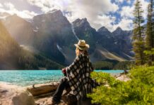 Frau sitzt in der Natur und genießt die Aussicht auf den See und die Berge