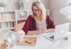 hübsche blonde Frau sitzt mit Brille vor Laptop und macht Home Office