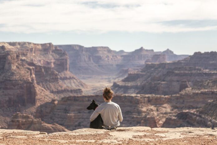 Frau sitzt mit ihrem Hund am Grand Canyon